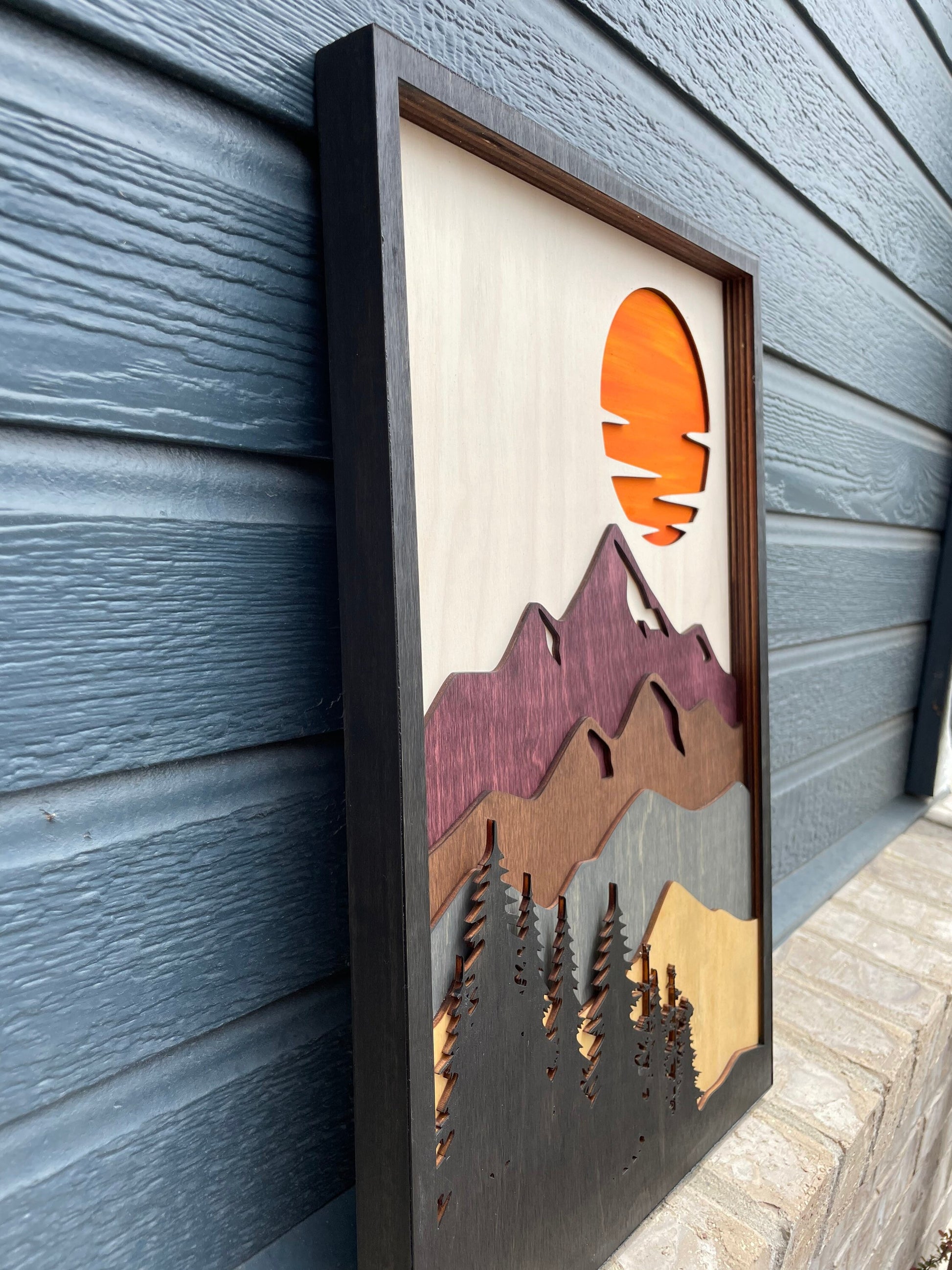 Side view of Beautiful mountain range with a vibrant orange sunset in the sky. Wooden wall art with 7 layers. Black trees, multi-colored mountain range wall art. Colorado Rocky Mountain wall hanging.